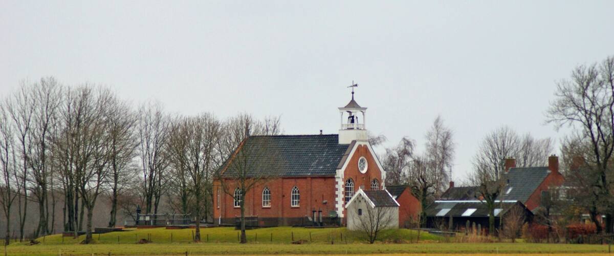 A red brick church with a white steeple and a small bell tower.