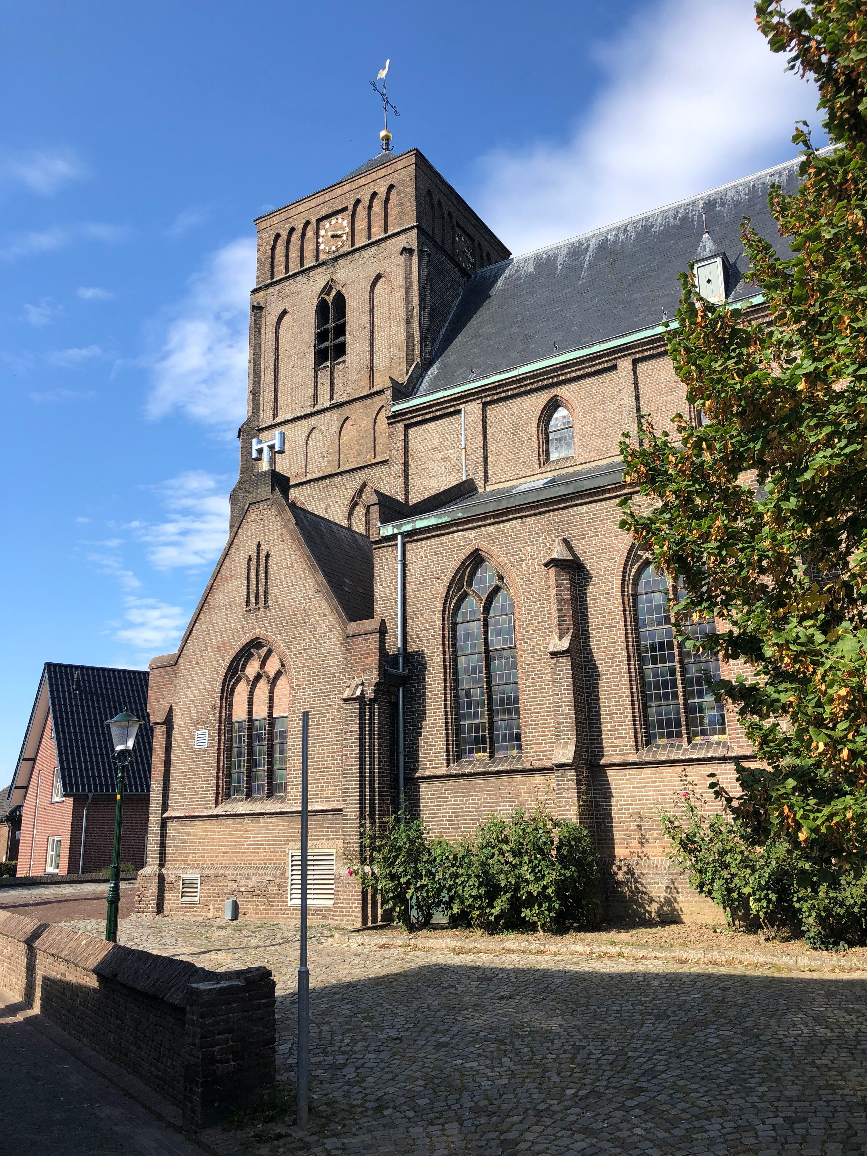 En historisk murstenskirke med et markant tårn og spidsbuede vinduer.