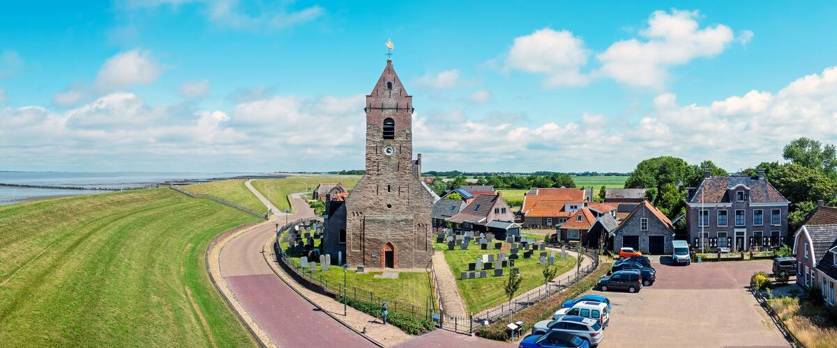 A coastal town with a prominent church tower, a cemetery, and houses along the waterfront.