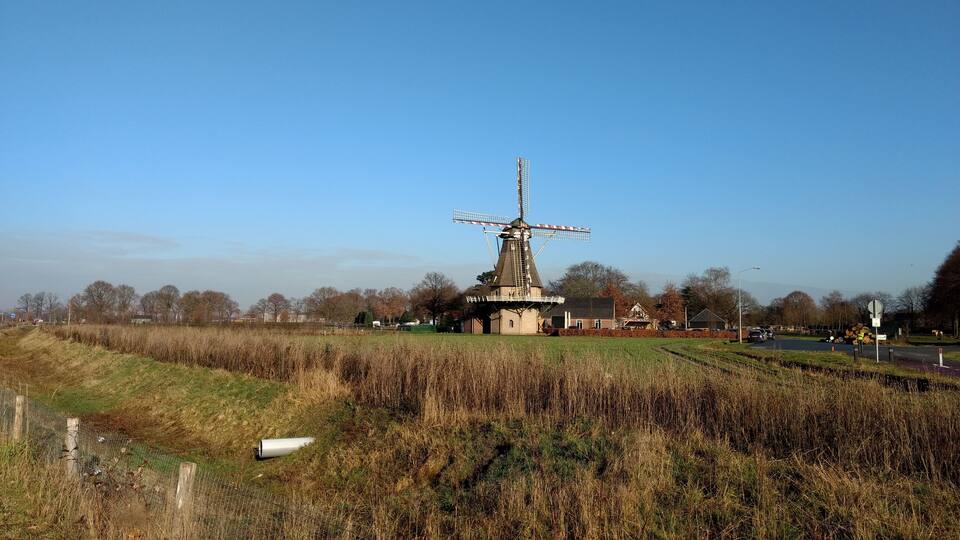 A windmill, a building, and a field.