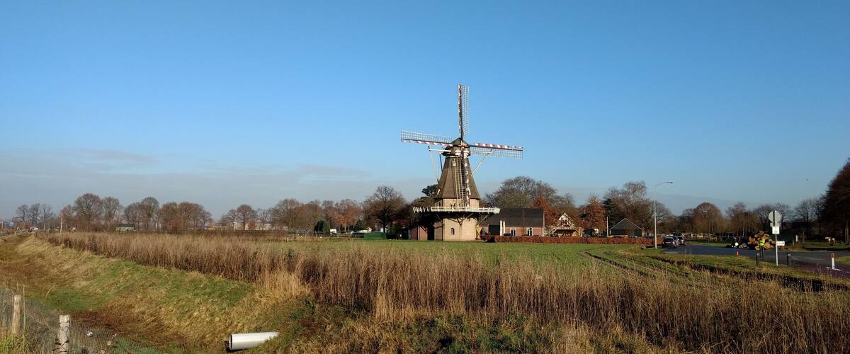 A windmill, a building, and a field.