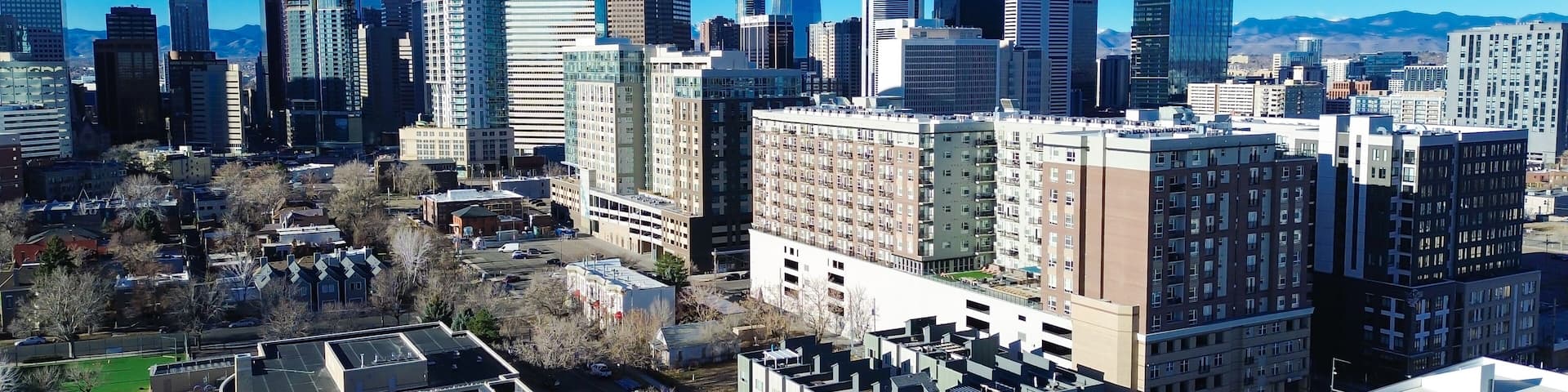 Uptown corridors stretch toward the central business district along 17th St. Bright skies emphasize reflective glass tower facades, varied roof textures and dormant branches, Denver, Colorado