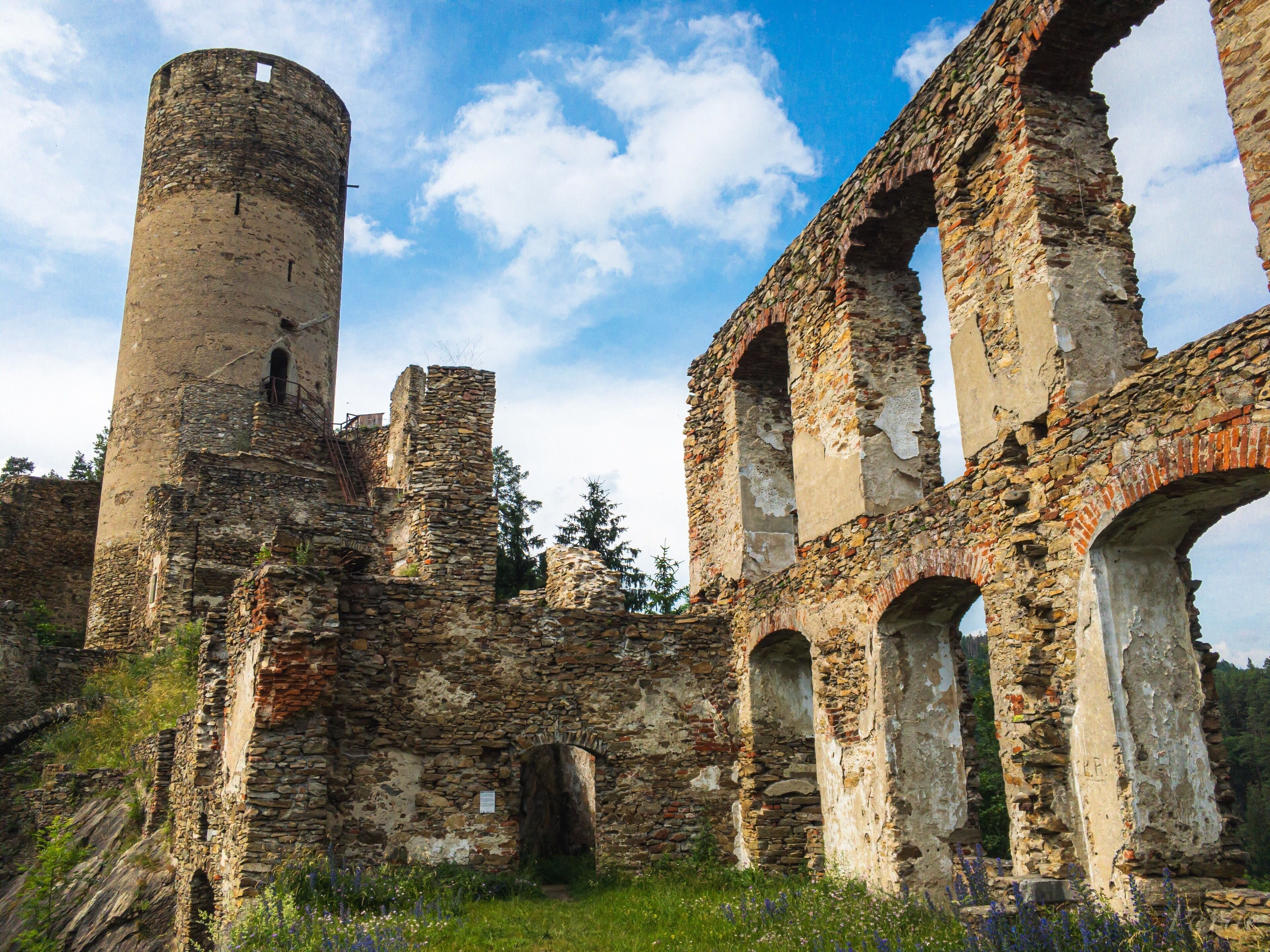 An ancient stone structure with arches and a cylindrical tower.