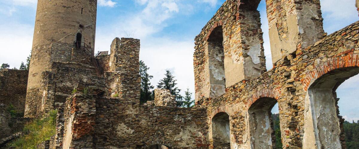 An ancient stone structure with arches and a cylindrical tower.