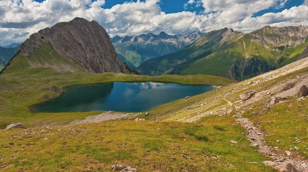 July 2015
Kogelsee, Lechtaler Alps
Kogelsee lake in 2.171 m altitude is one of the many lakes in Lechtaler Alps in Tirol, Austria. On the left the Kogel (2.318 m) and to the right the green meadows of Taja Spítze (2.352 m). In the background in middle there are the Allgaeuer Alps behind the Lech river valley (= Lechtal).
This is the route from Gramais village (1.437 m) to Hanauer Huette over Kogelseescharte saddle. It is a demanding 5 hours trek, day 1 of our 4-days trek in Lechtaler Alps this summer.