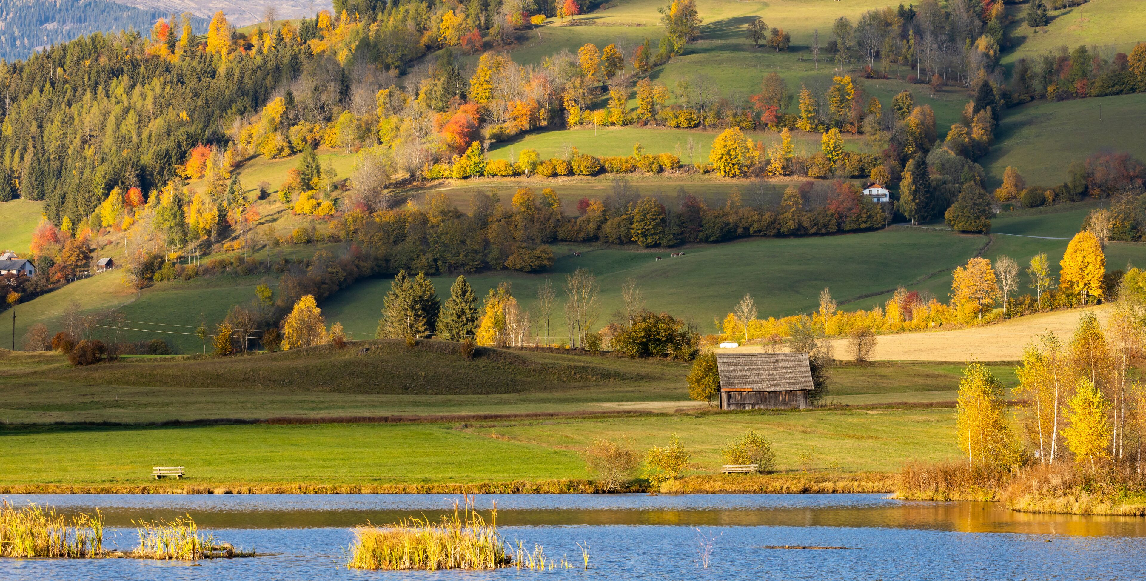 A lake surrounded by autumn-colored trees and rolling hills.