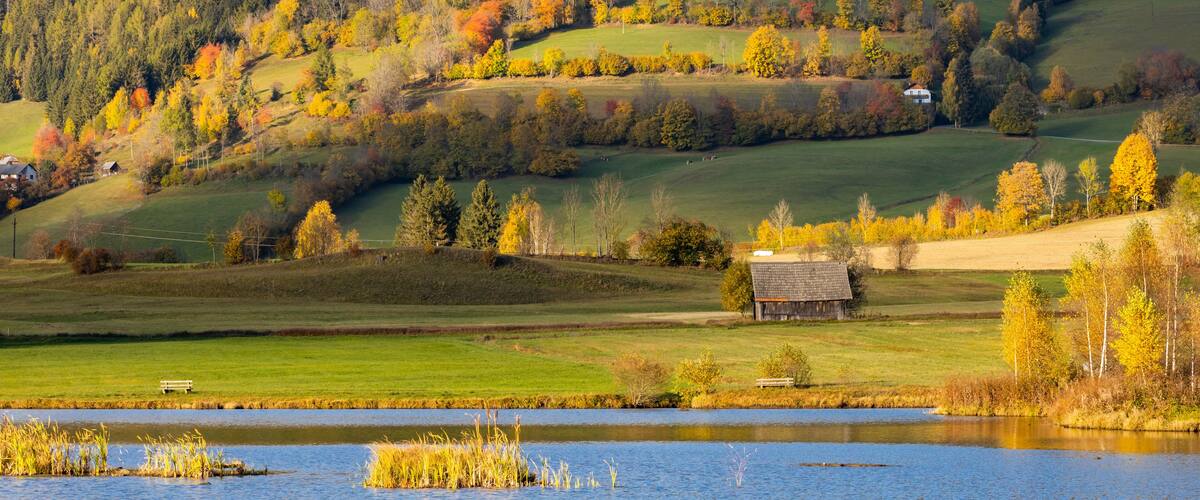 A lake surrounded by autumn-colored trees and rolling hills.