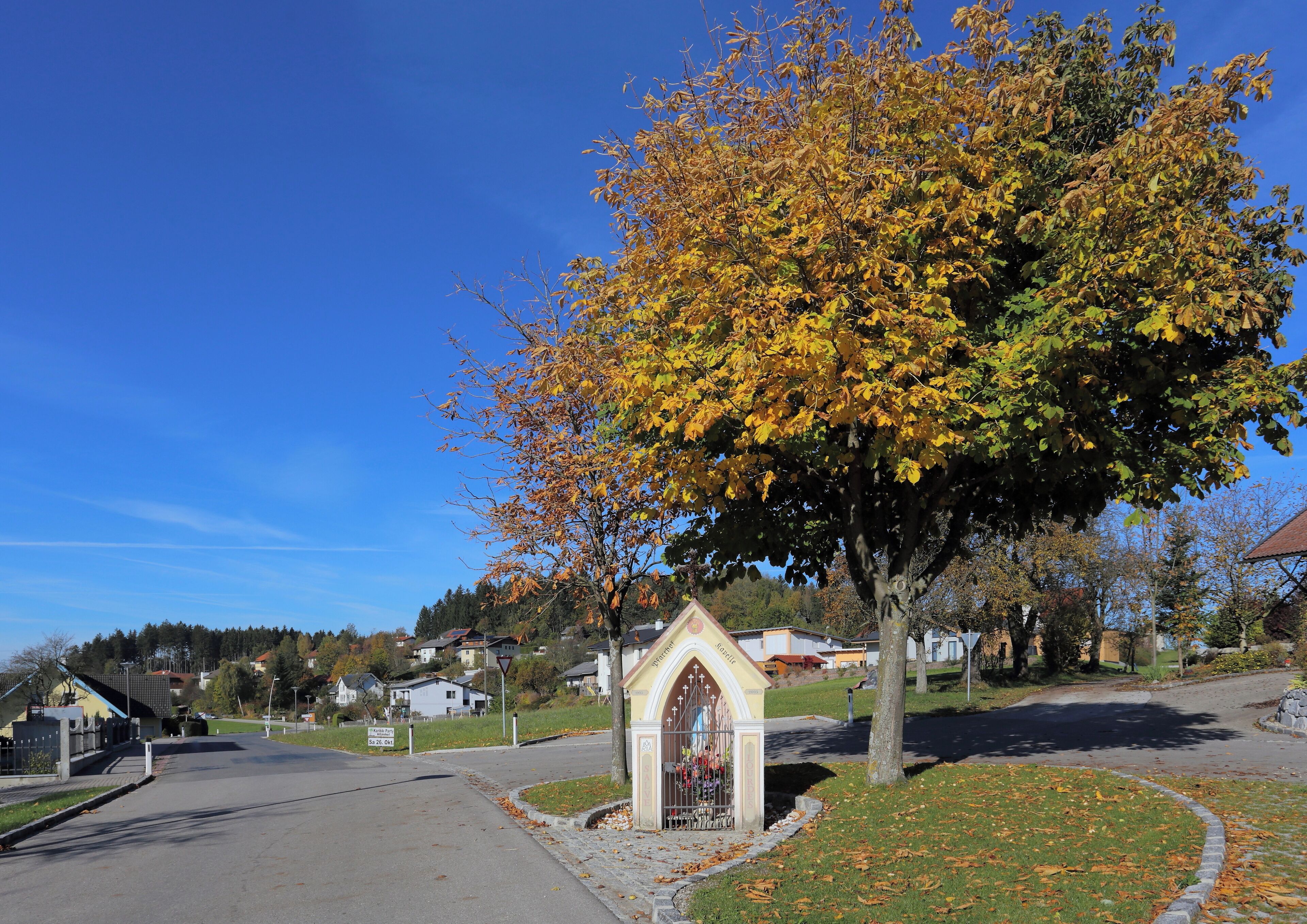 A residential street with houses, a church, and autumn foliage.