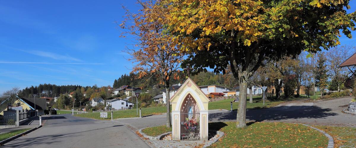 A residential street with houses, a church, and autumn foliage.