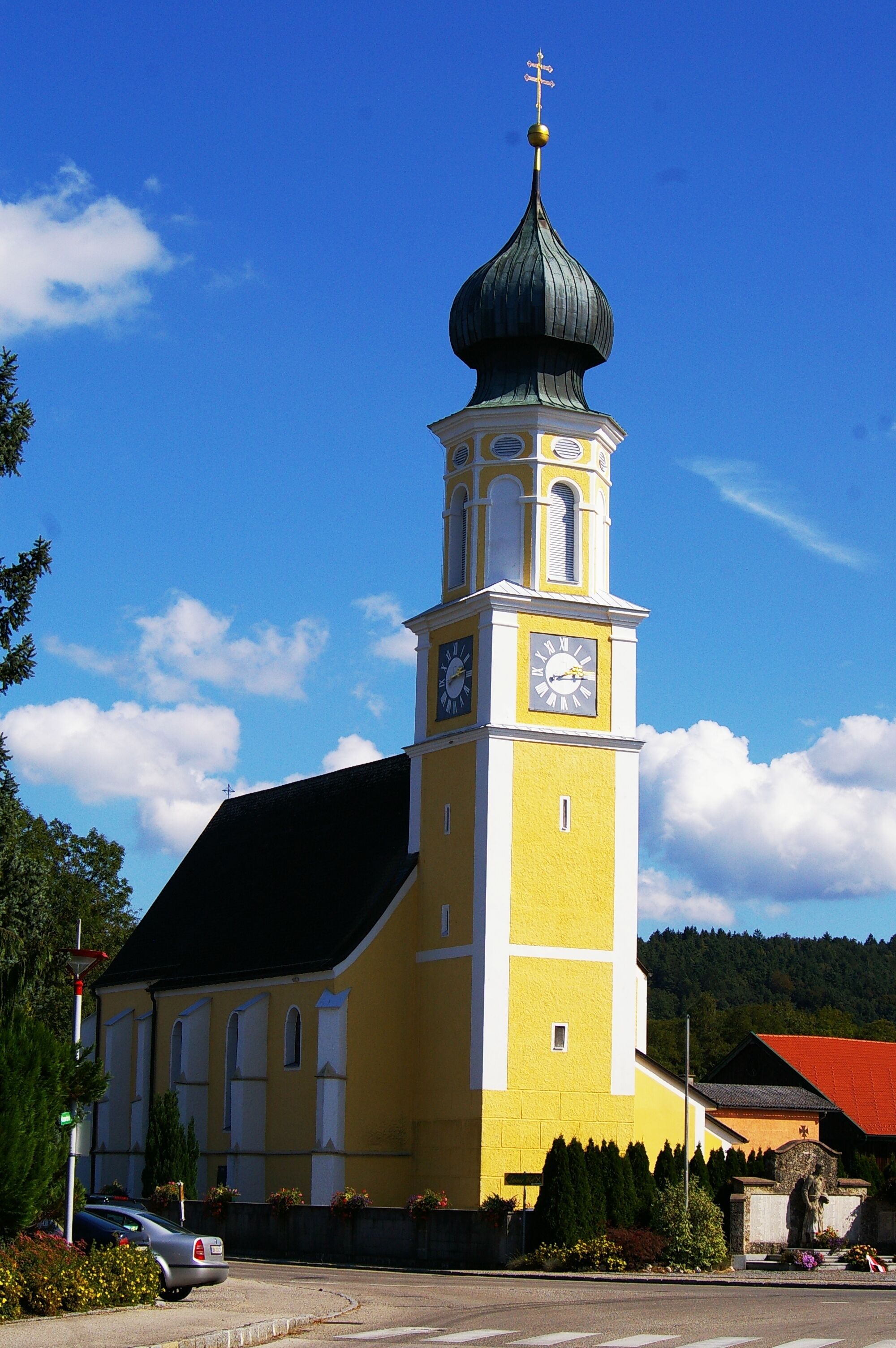 A yellow church with a clock tower and a green dome.