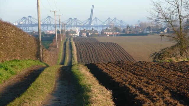 Shotley - rolling fields Footpath to Shotley Gate. The telephoto lens foreshortens the view of the cranes at Felixstowe on the other side of the river Orwell.