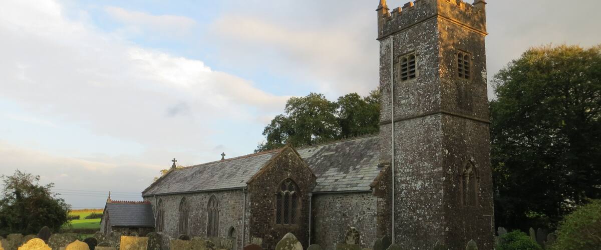 A historic church with a tall tower and a graveyard in the foreground.