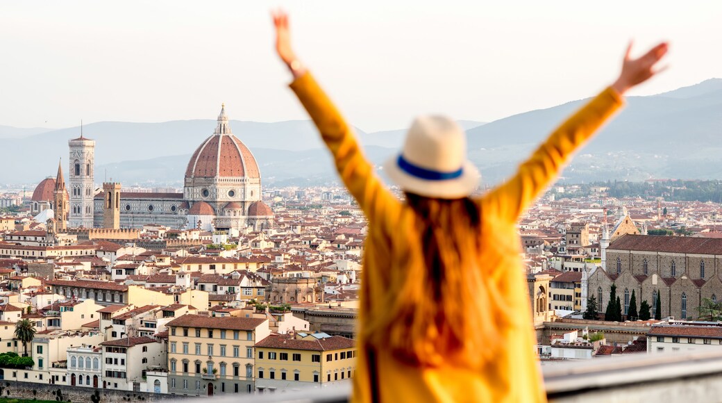 Young female tourist with raised hands looking on the old town of Florence from Michelangelo square in the morning in Italy. Back focus; Shutterstock ID 474019549