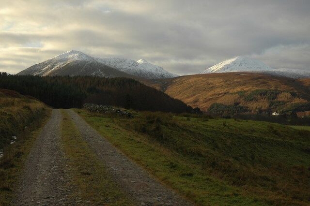 A gravel road leading to a mountain with snow-capped peaks.