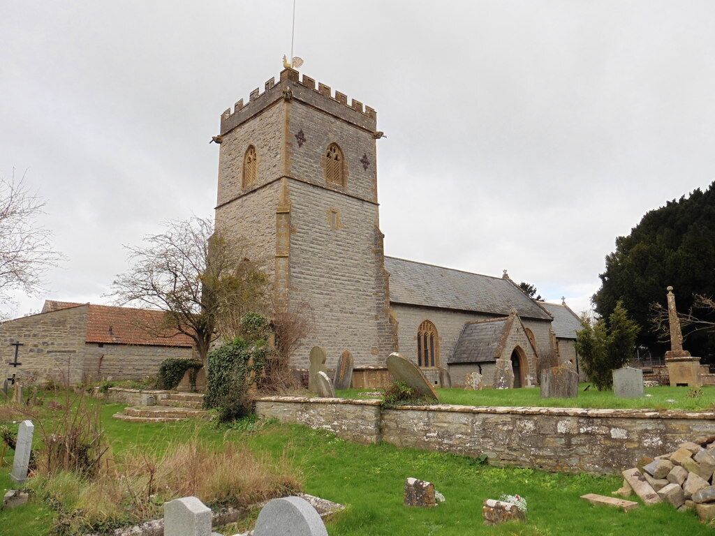 A stone church with a tall tower and a cemetery in the foreground.