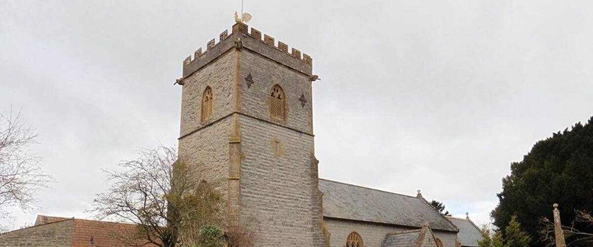 A stone church with a tall tower and a cemetery in the foreground.
