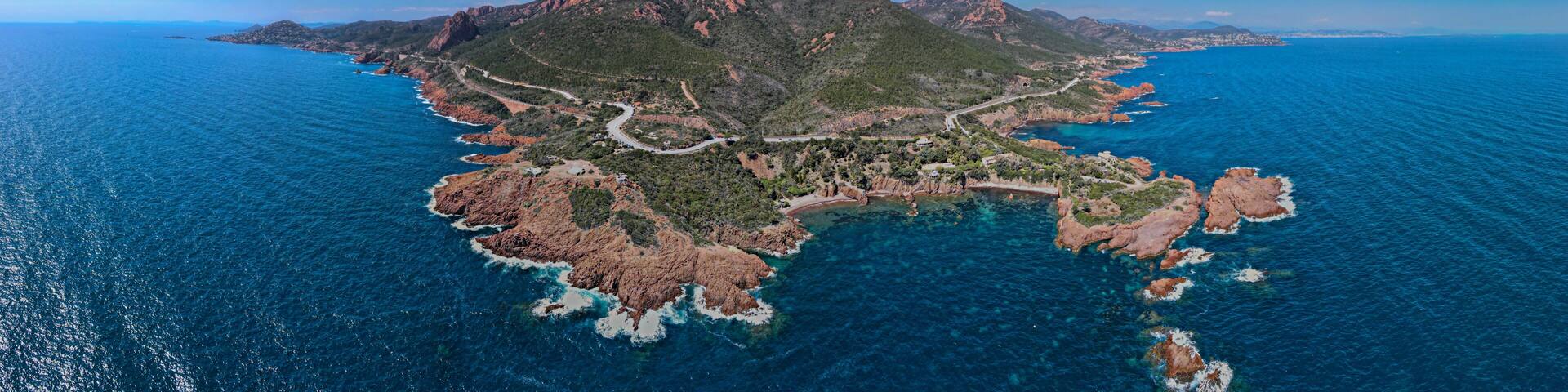 A rugged island with a winding road and clear blue waters.