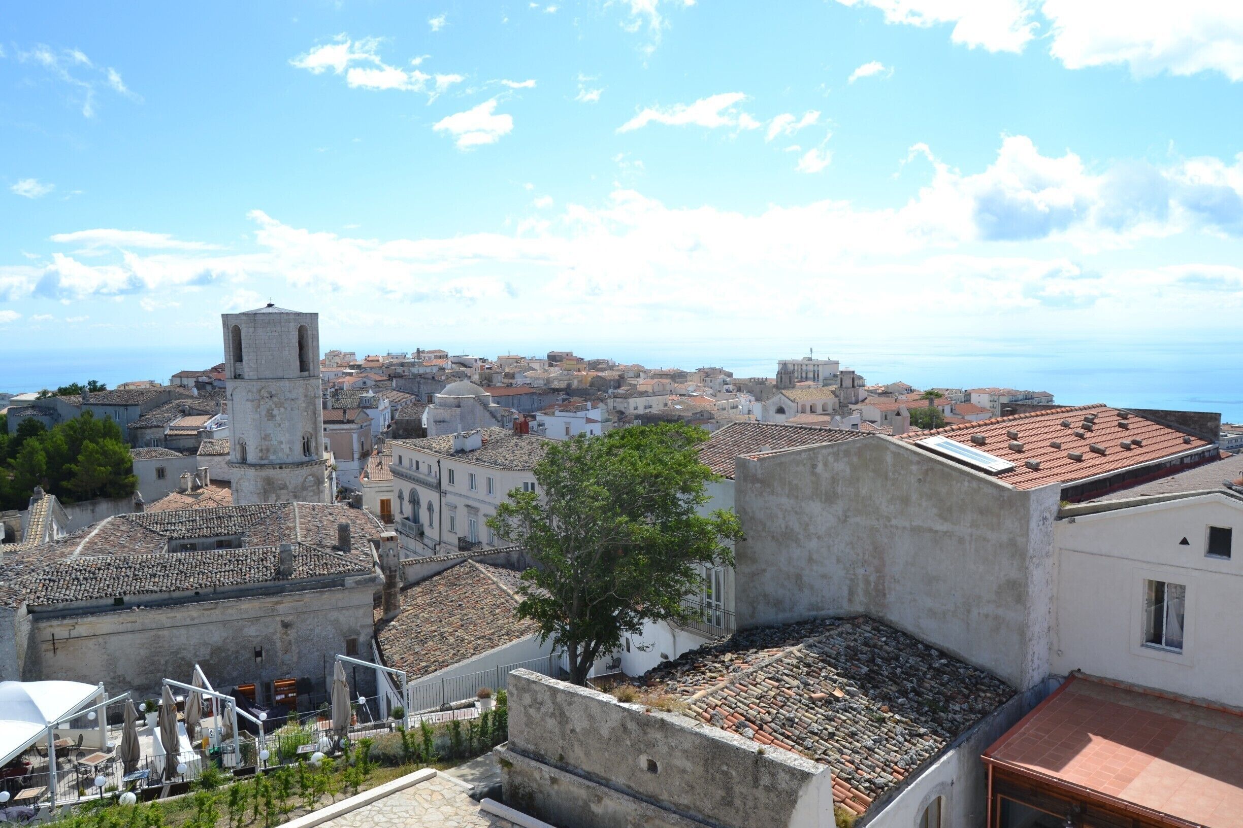 A coastal town with historic buildings, a prominent tower, and a clear view of the sea.