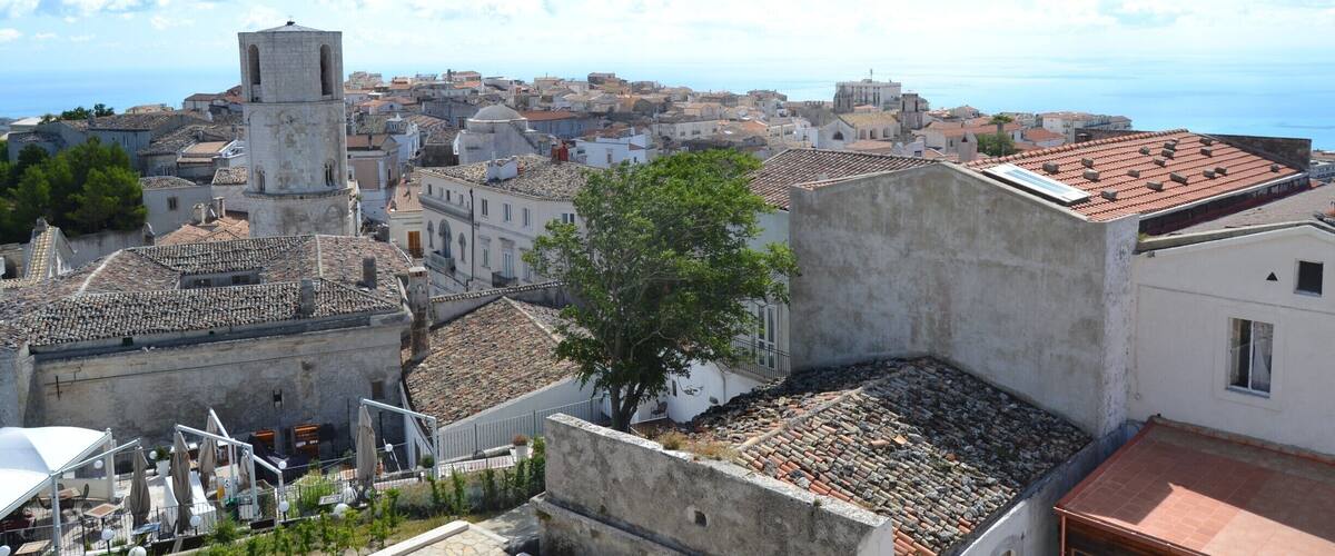 A coastal town with historic buildings, a prominent tower, and a clear view of the sea.