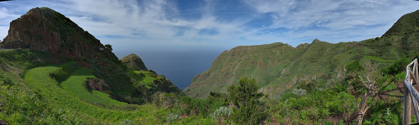 A mountainous landscape with a valley and a view of the ocean.