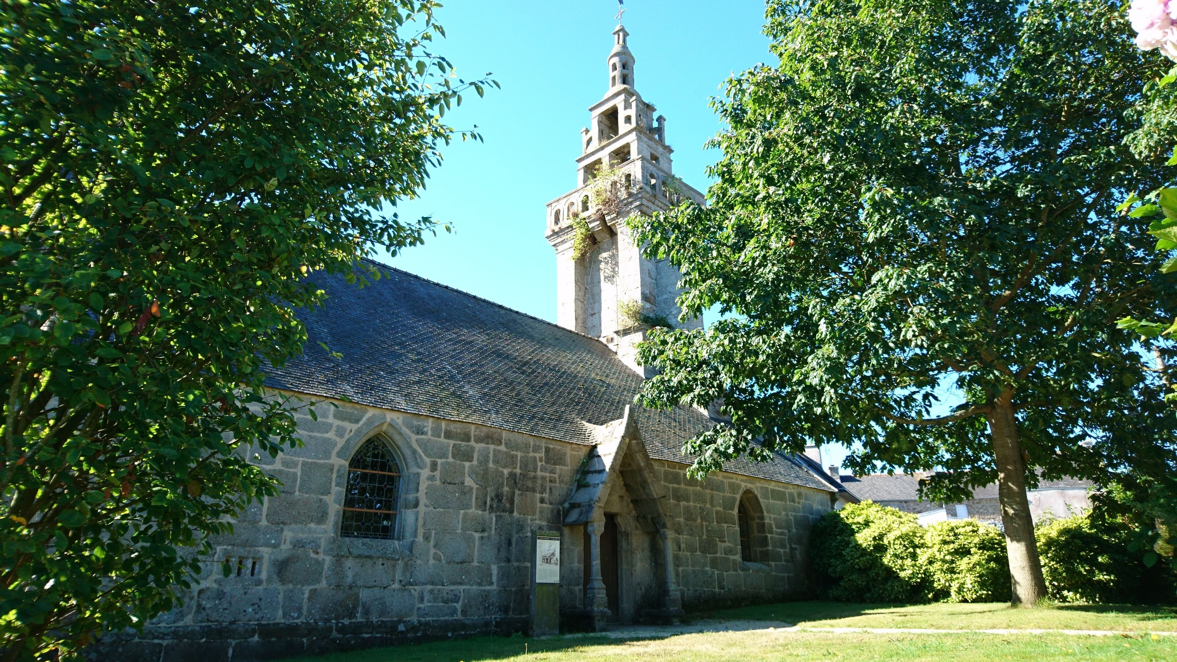 A stone church with a tall bell tower and arched windows.