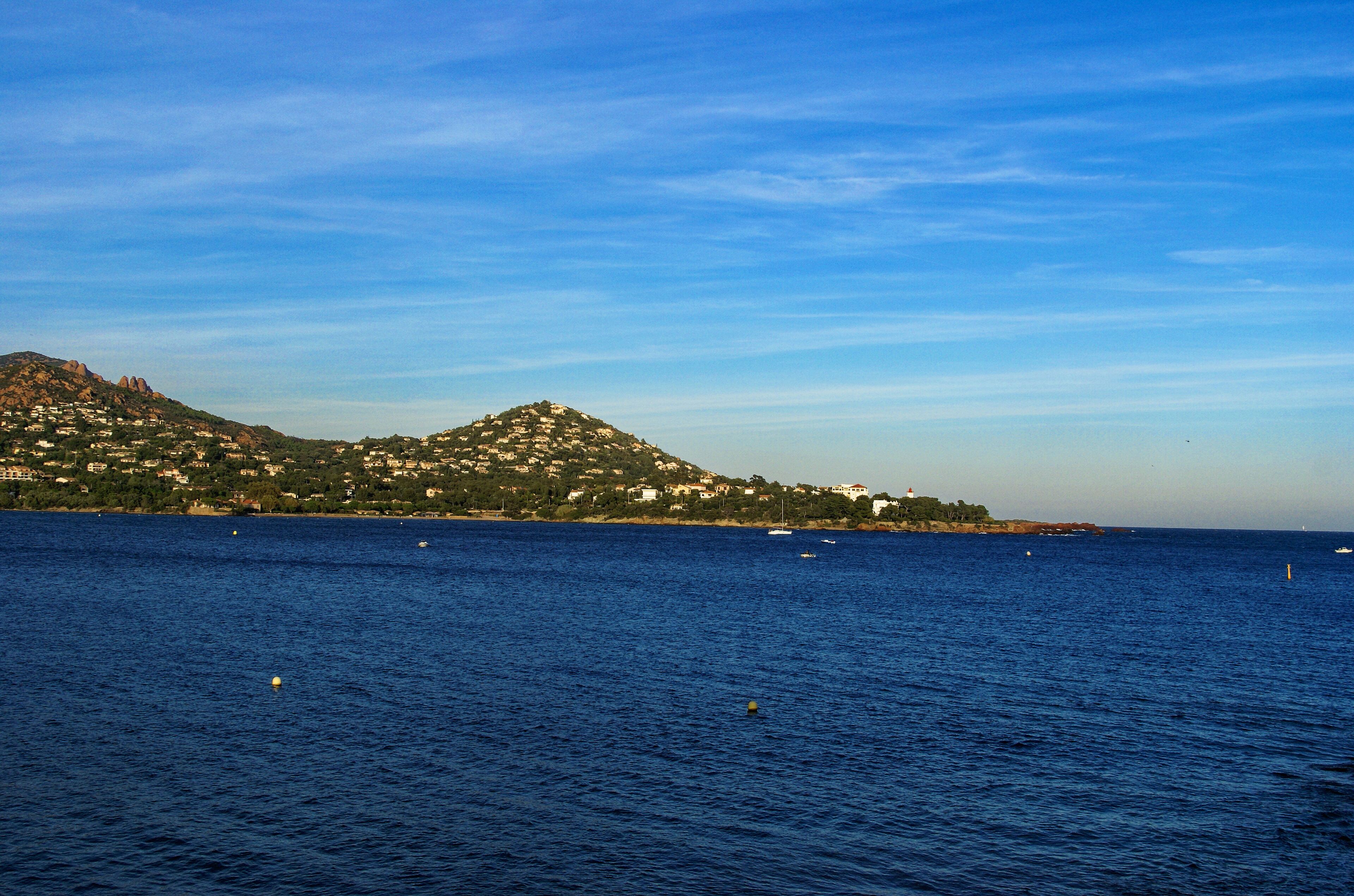 A coastal town with a hill, houses, and boats on the water.