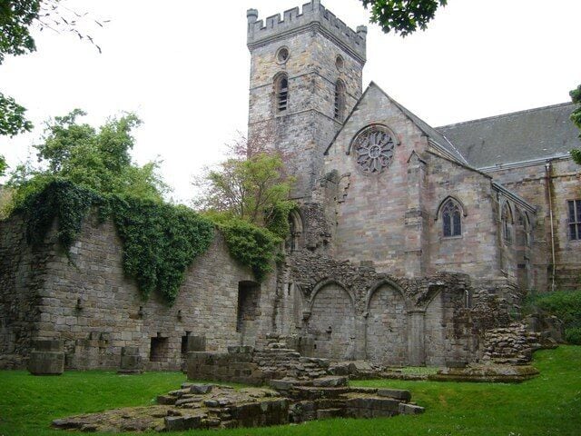 An old stone church with a clock tower and ivy-covered walls.