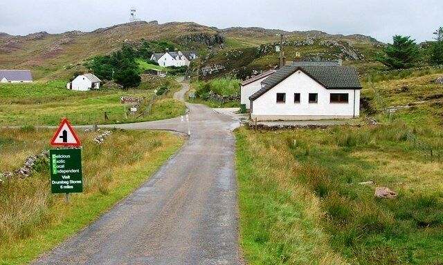 Turn Off to Stoer Lighthouse. The building opposite the junction is the village community hall.