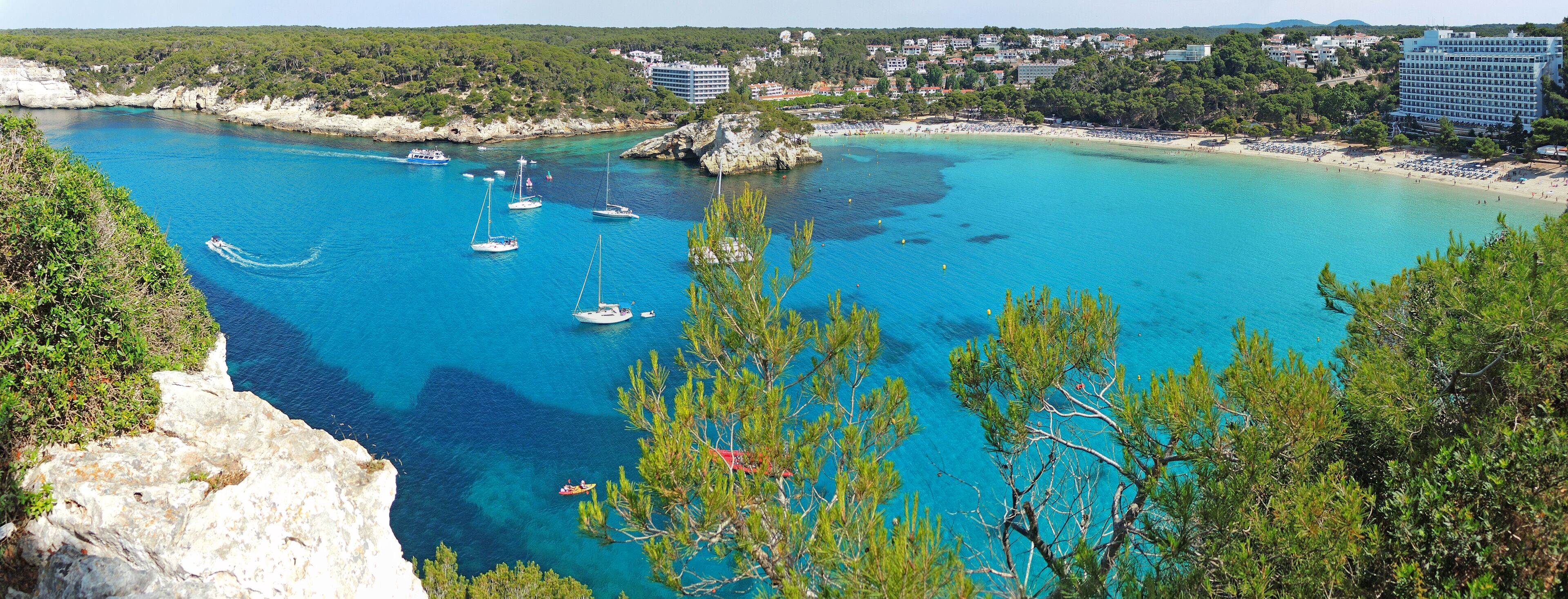 A coastal town with clear turquoise waters, boats, and a beach.