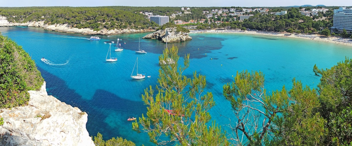 A coastal town with clear turquoise waters, boats, and a beach.