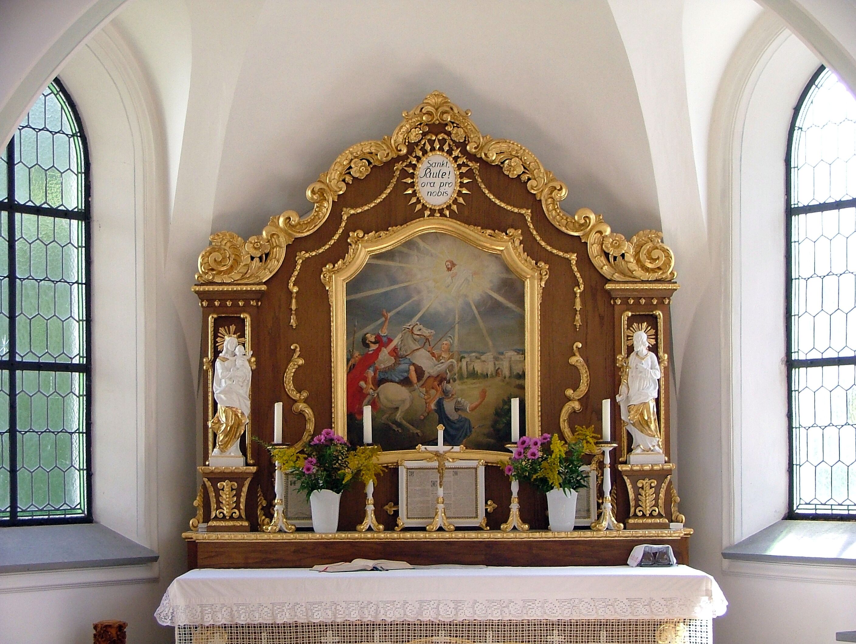 A religious altar with ornate gold detailing, a central painting, and statues.