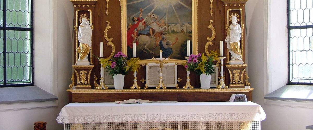A religious altar with ornate gold detailing, a central painting, and statues.