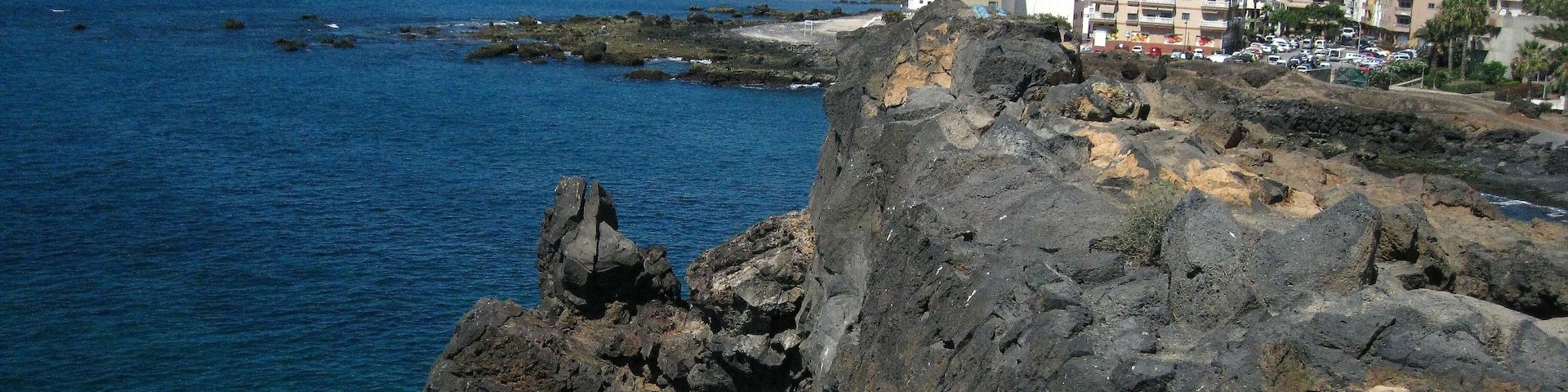 A rocky coastline with buildings in the background.