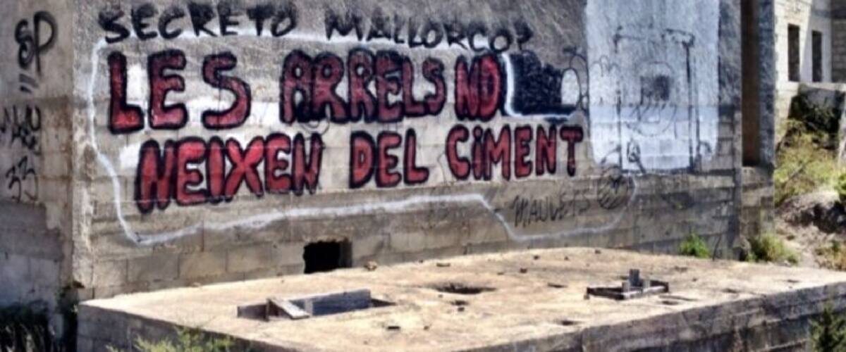 A building with graffiti that reads "SECRETO MALLORCO LES ARRELS ND NEIXEN DEL CIMENT".