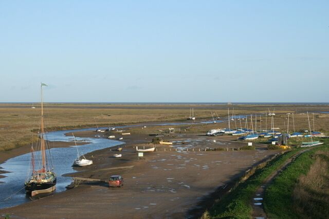 A coastal area with boats docked along a sandy beach and a water channel.