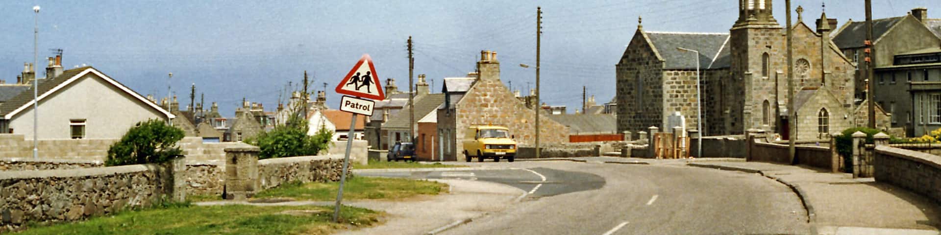Cairnbulg: site of station, 1988. View NE on B9107 to Inverallochy where the ex-GNS Fraserburgh (left) - St Combs (right) light railway crossed. The station and line were closed from 3/5/65.