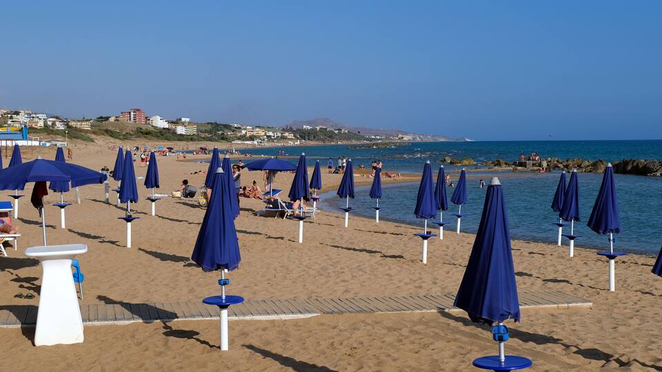 A beach with rows of blue umbrellas and lounge chairs.