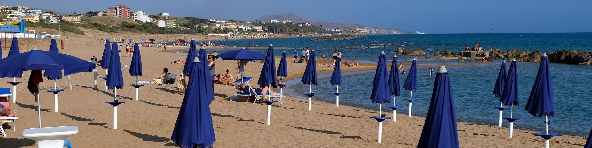 A beach with rows of blue umbrellas and lounge chairs.