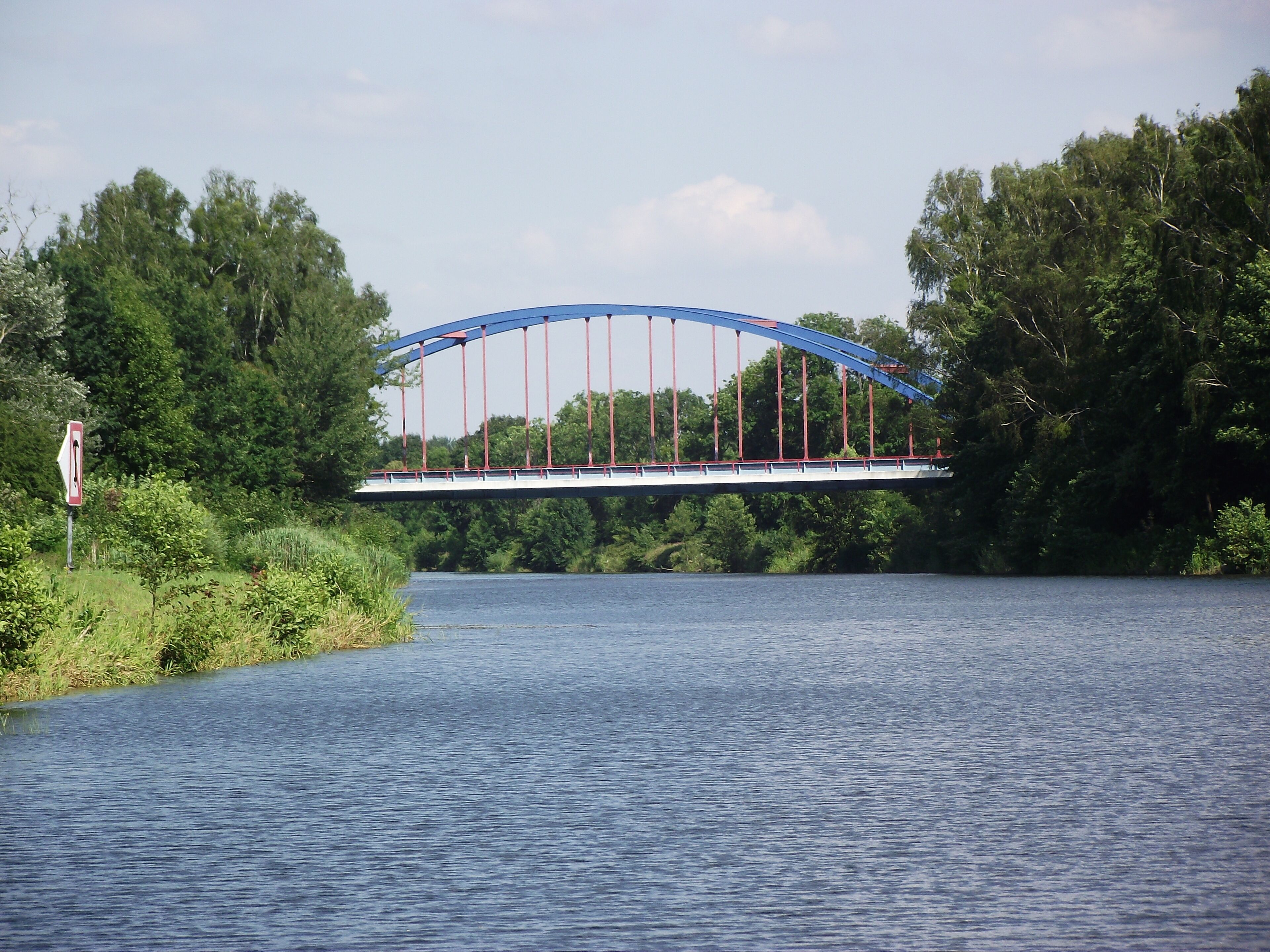 A bridge over a river with dense trees on both sides.
