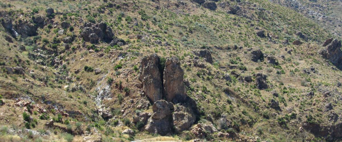 A winding mountain road surrounded by rocky terrain and sparse vegetation.