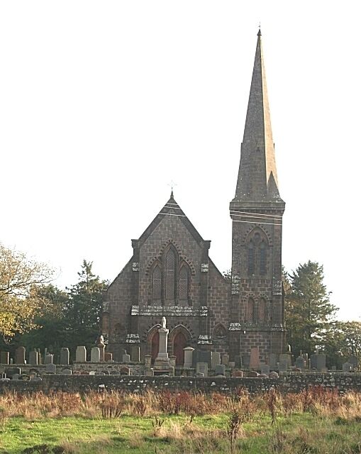 A church with a tall spire and a stone wall with gravestones.