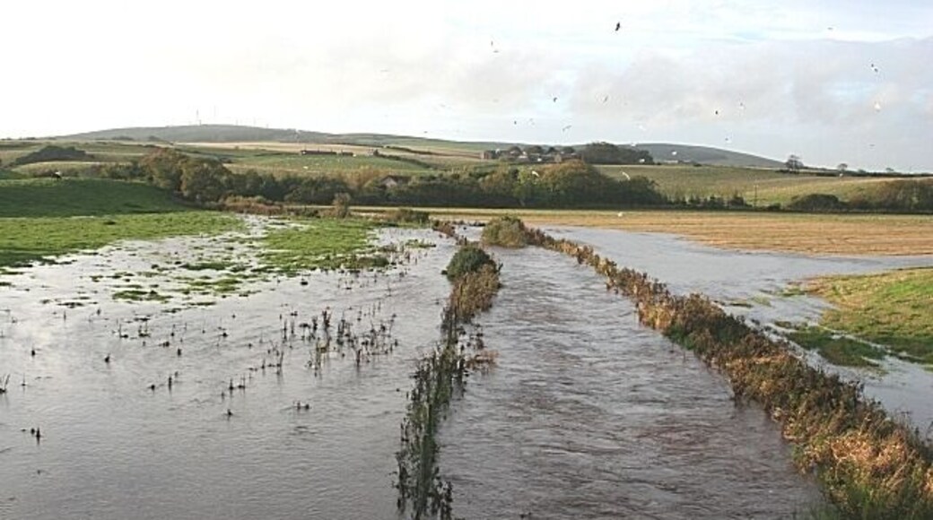 Flood at Rathen The burn here was in spate after several days of heavy rain. In the distance is Mormond Hill.