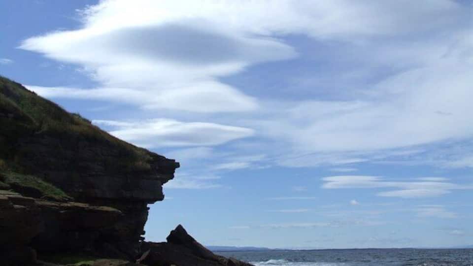 A rocky coastline with cliffs and a clear sky.
