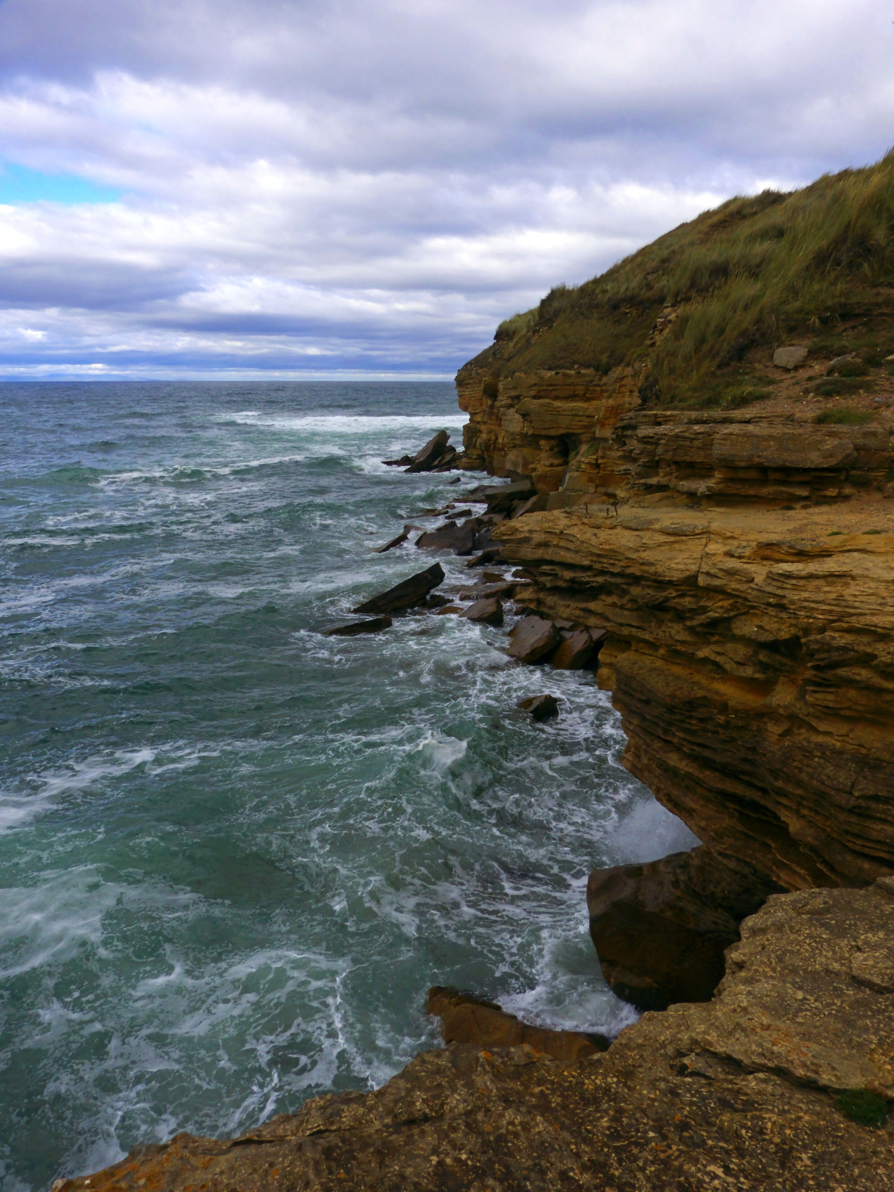 A rocky coastline with waves crashing against the cliffs.