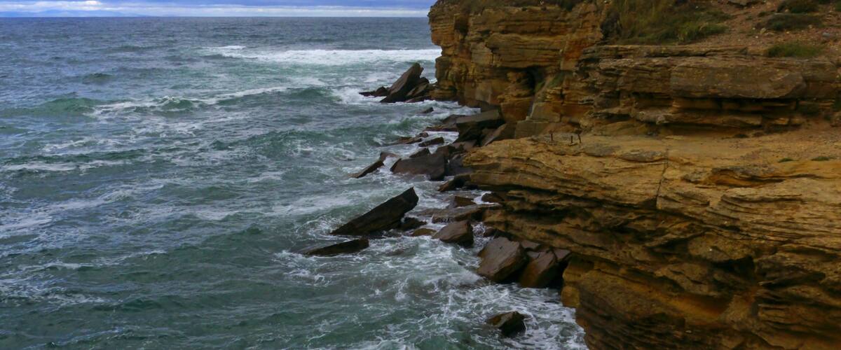 A rocky coastline with waves crashing against the cliffs.