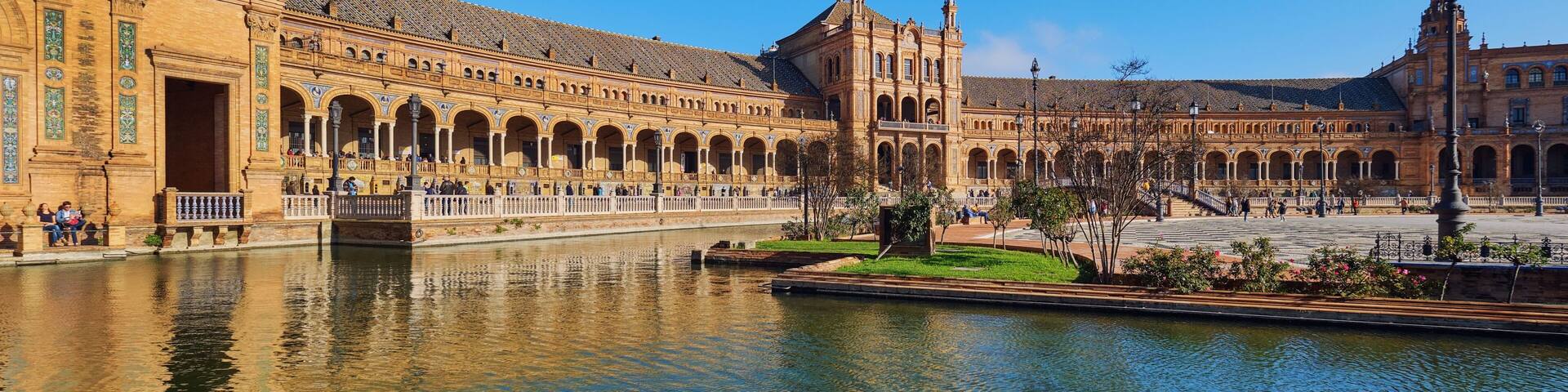 A historic building with arches and a river in the foreground.