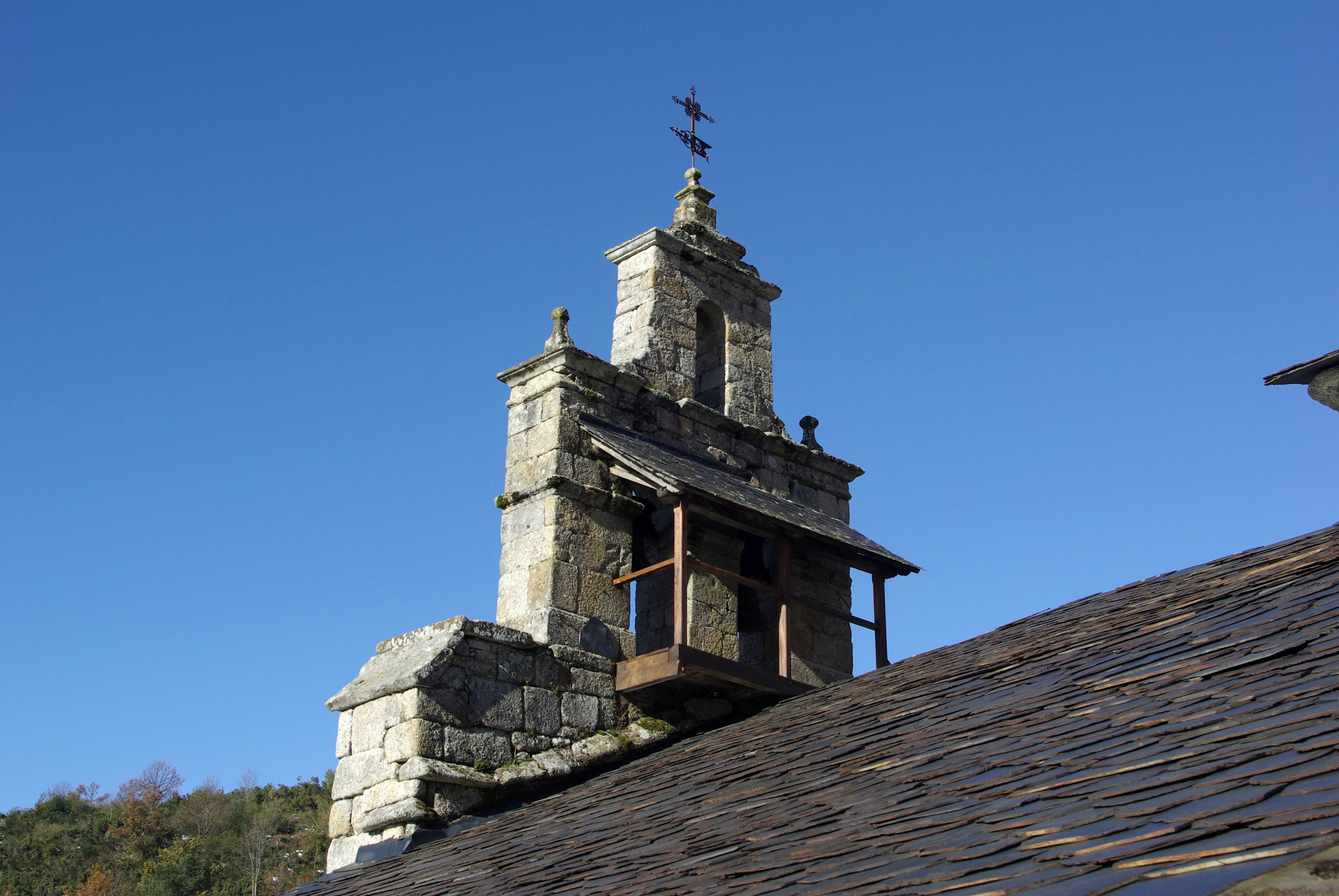 A stone bell tower with a weather vane on top.