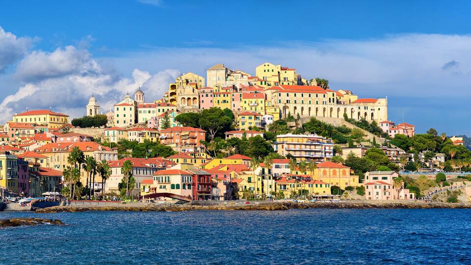 A coastal town with colorful buildings, a prominent church, and a rocky shoreline.