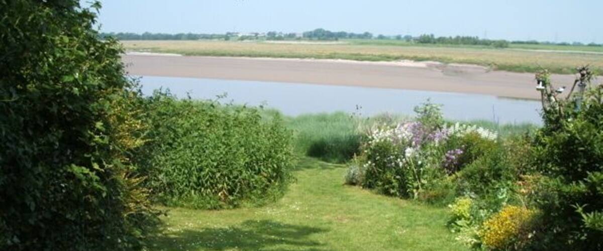 A grassy path leading to a body of water with a clear sky.