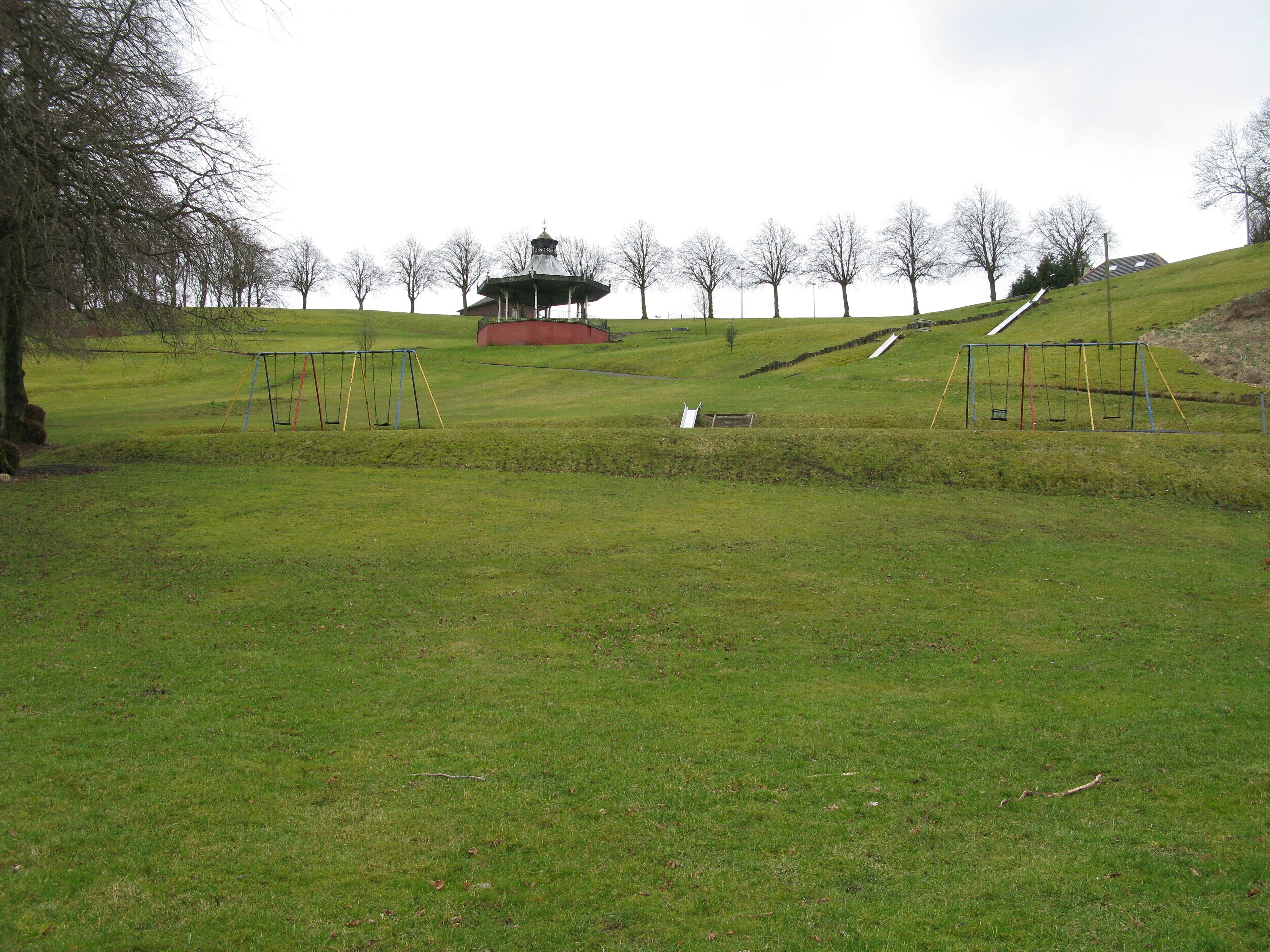 A park with a gazebo, swings, and a grassy hill.